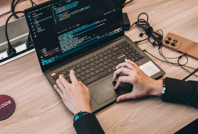 A person coding on a laptop with a Lexcode branded coaster at the left-hand side.