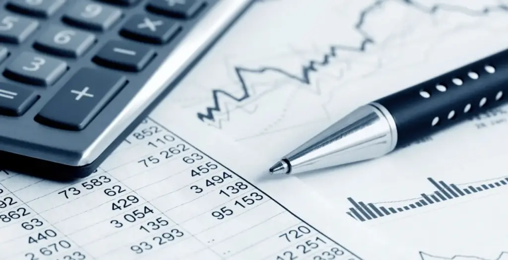 A pen, paper, and calculator. This image represents computation and charts.