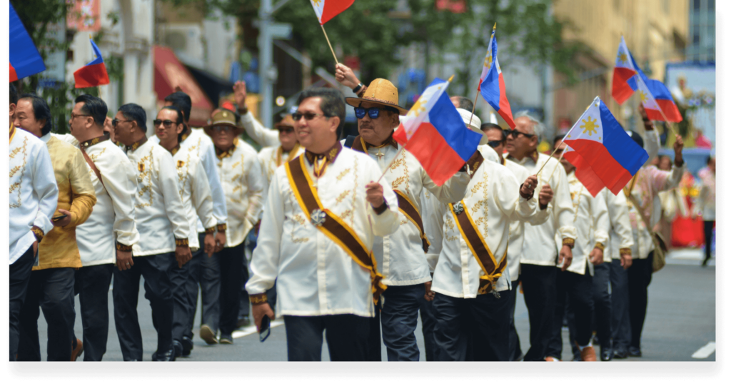 A filipino parade with filipinos waving the Philippine Flag