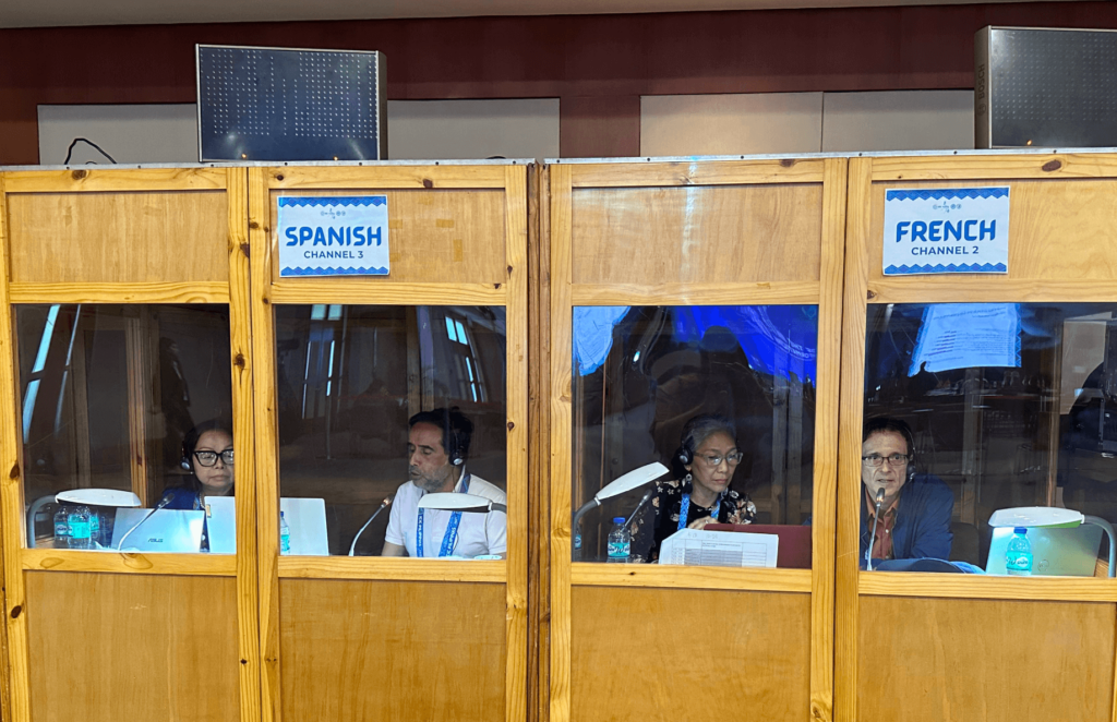 Interpreters in Spanish and French booths providing language services during an international conference.