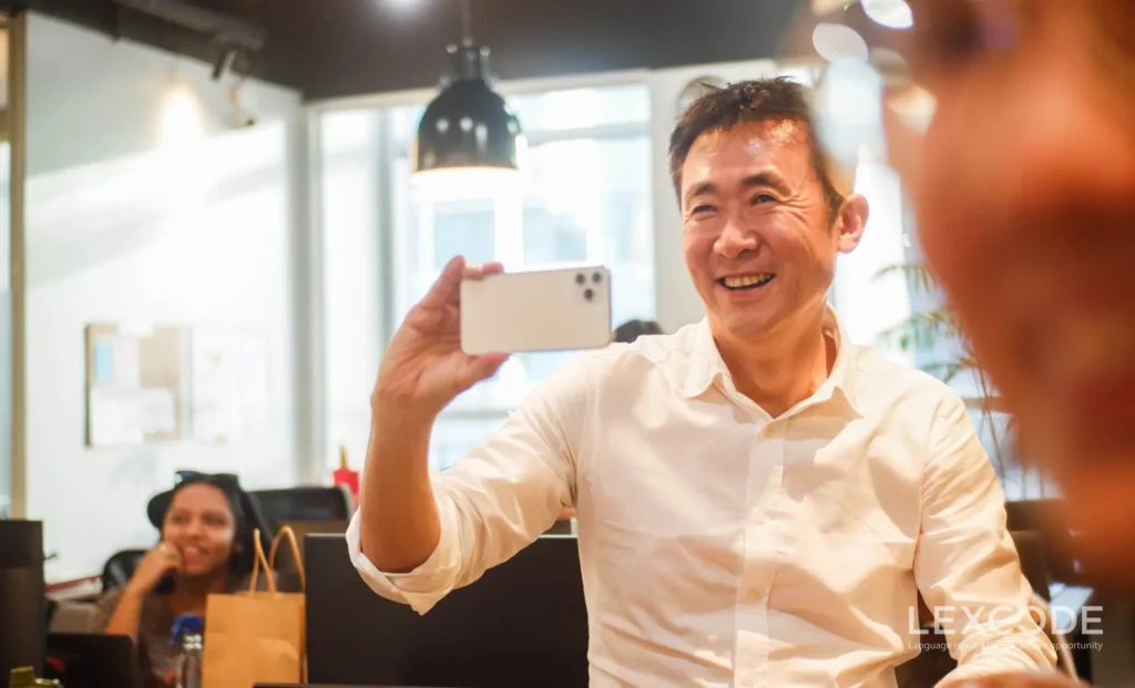 A man, the company’s CEO, takes photos and videos on his phone with a smile on his face.