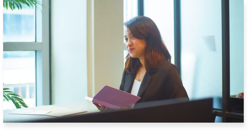 Ms. Andie holding a book beside our office window