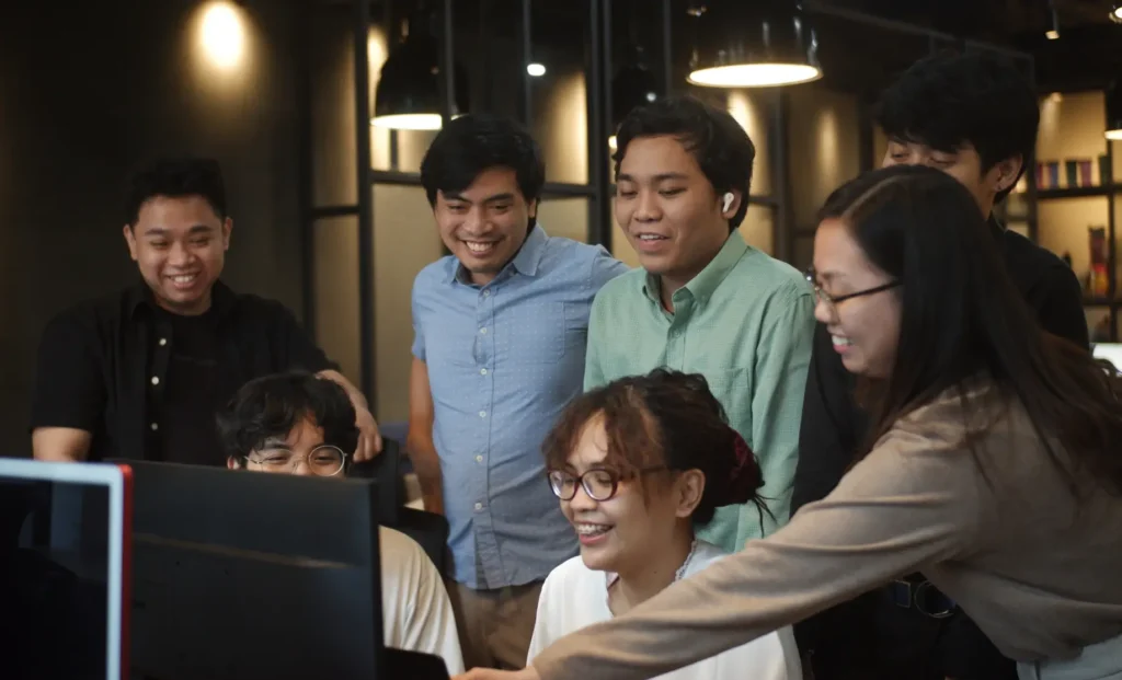 Lexcode employees gathered around a computer in a modern office setting.