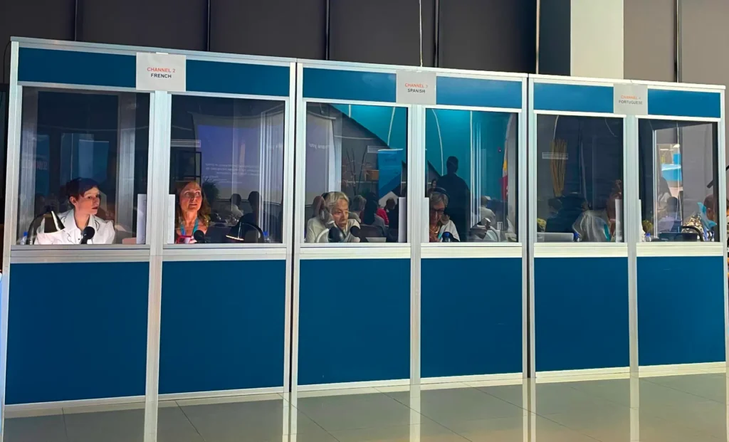 Multiple interpreter booths set up at an event, with interpreters actively providing translation services.