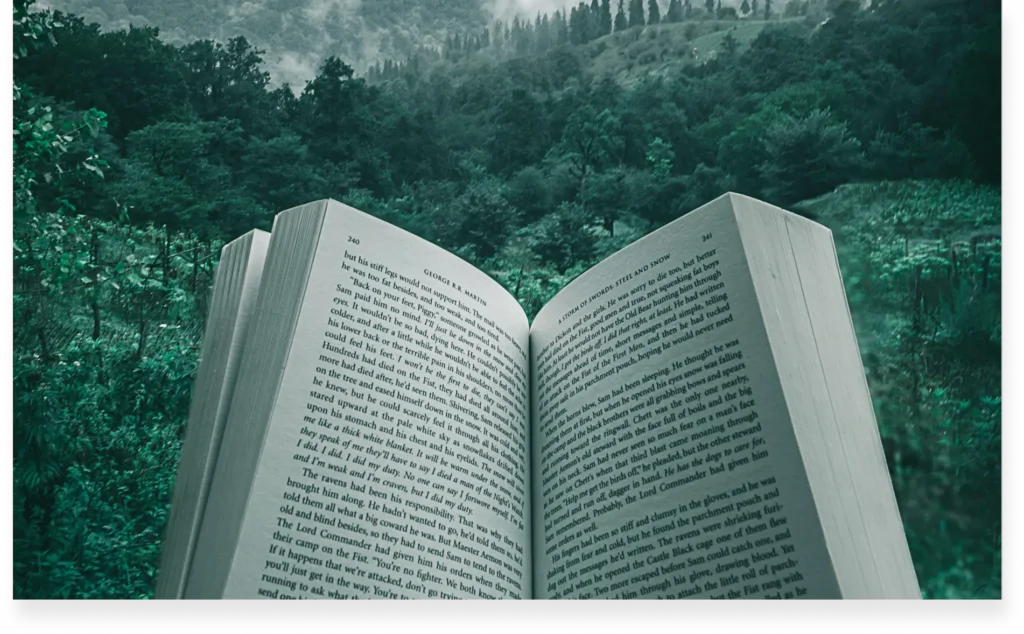 Open book with printed text against a lush green forest backdrop.