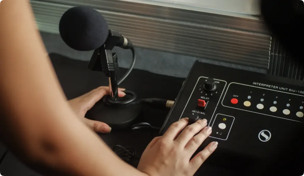 Close-up of hands operating professional interpreter unit control panel with microphone for simultaneous translation
