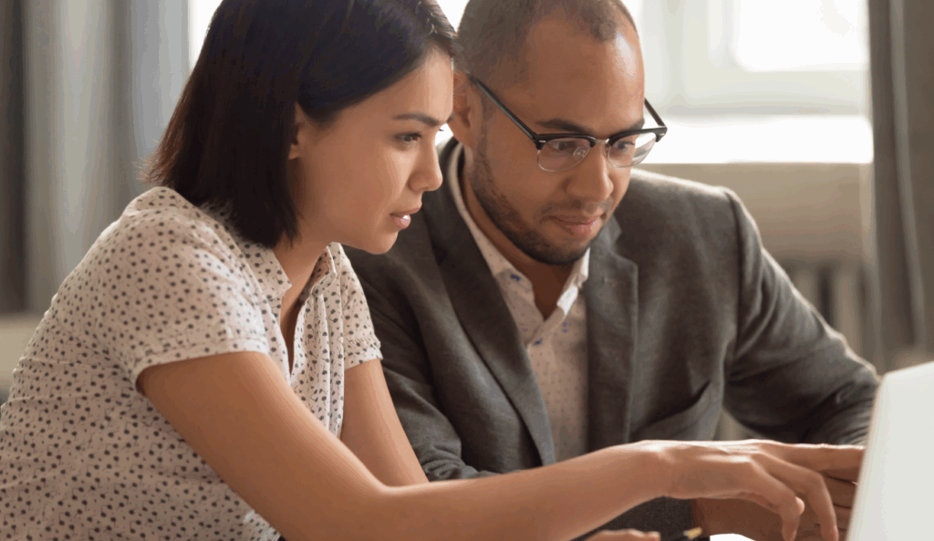 A woman and a man discussing something on a laptop, working together in a professional setting.