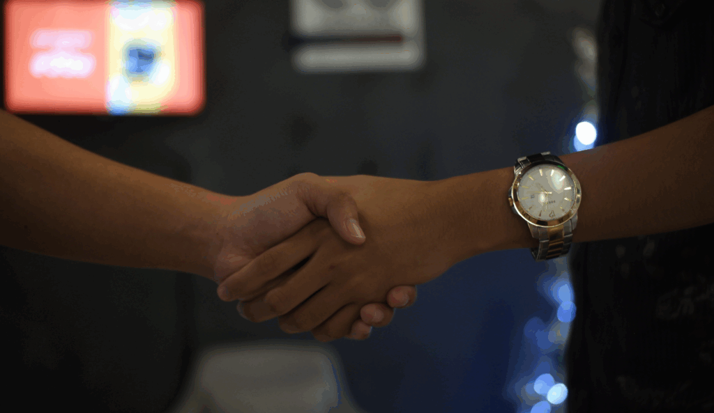 two people handshaking with watch in hand